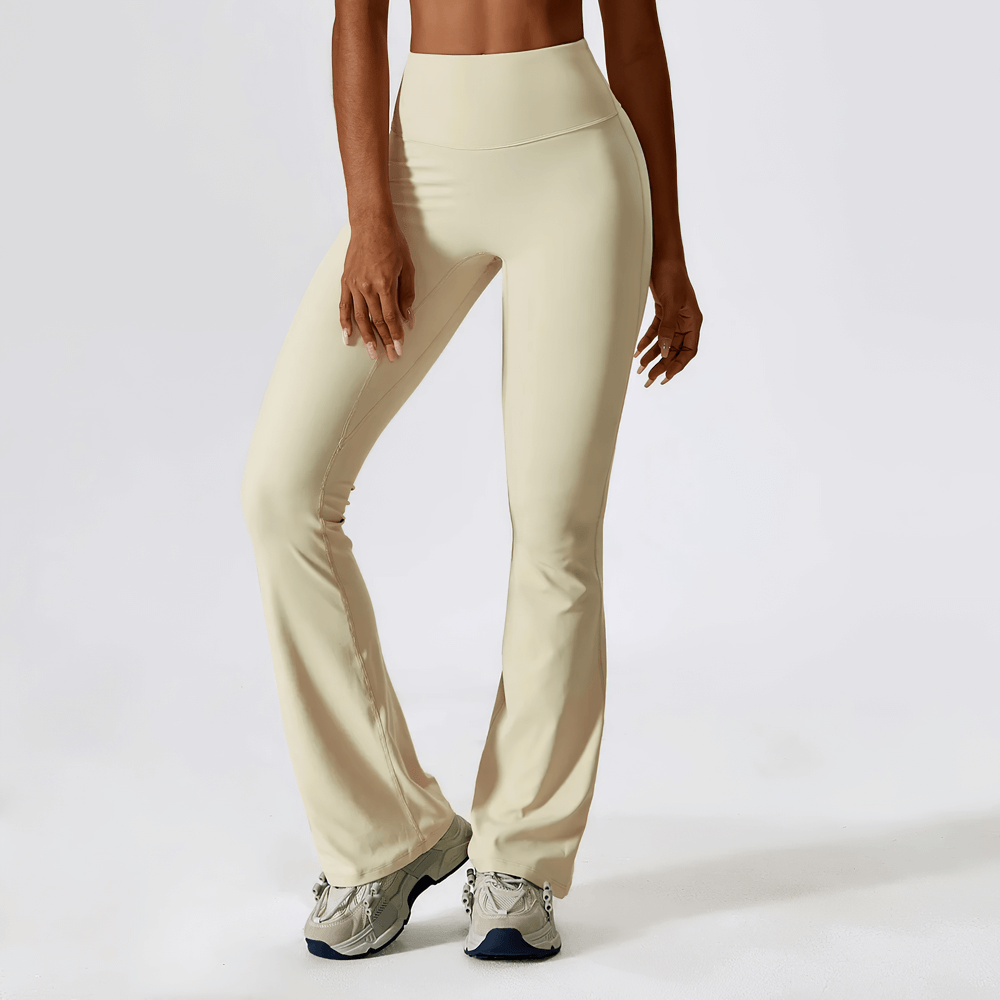 Woman wearing elastic high-waist flared yoga pants in cream color, ideal for fitness and dance. Wide-leg design offers comfort and style.