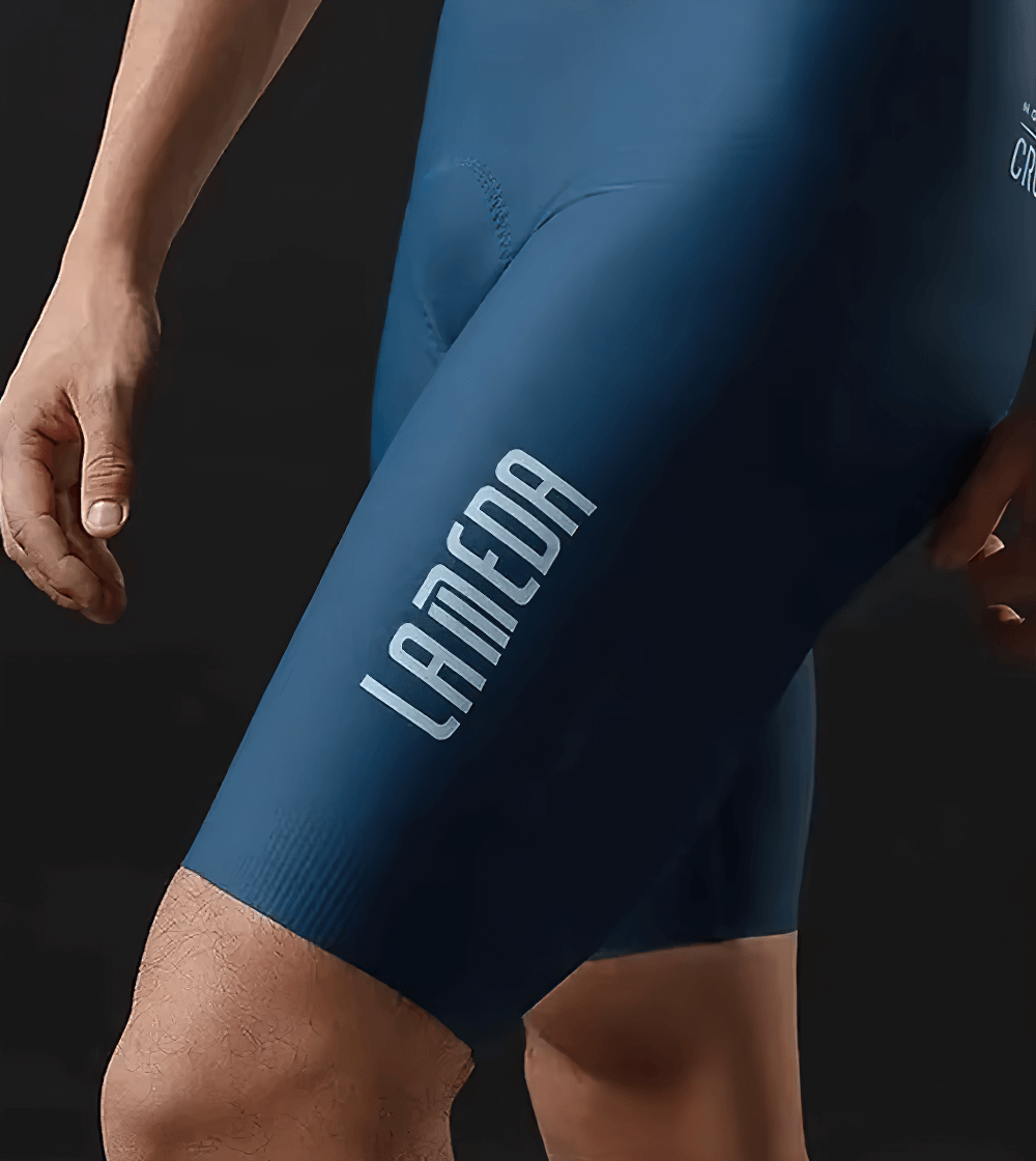 Close-up of men's blue cycling bib shorts with brand logo, showing stretchy and breathable fabric for optimal performance.