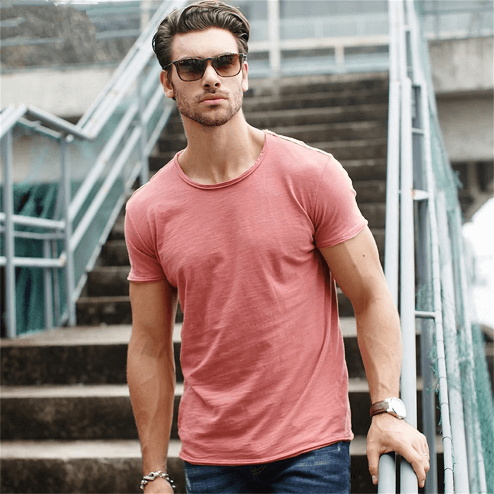 Casual and stylish man in a pink short sleeve t-shirt on stairs, showcasing comfort and modern style in an urban setting.