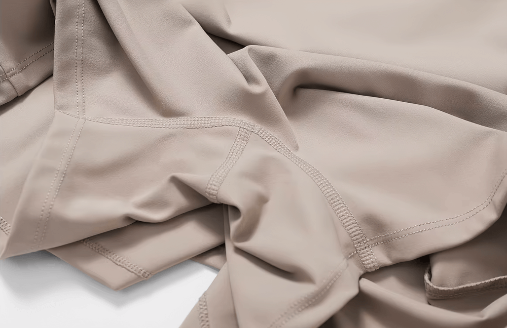 Close-up of beige elastic yoga dress fabric, showcasing breathable and durable material with detailed stitching. Perfect for activewear.