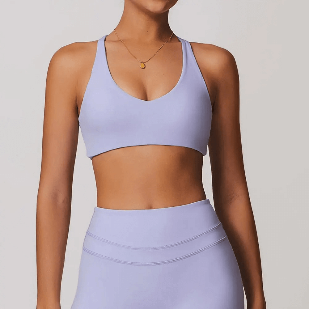 Woman wearing a light purple racerback sports bra with breathable fabric, ideal for yoga, running, and fitness activities.