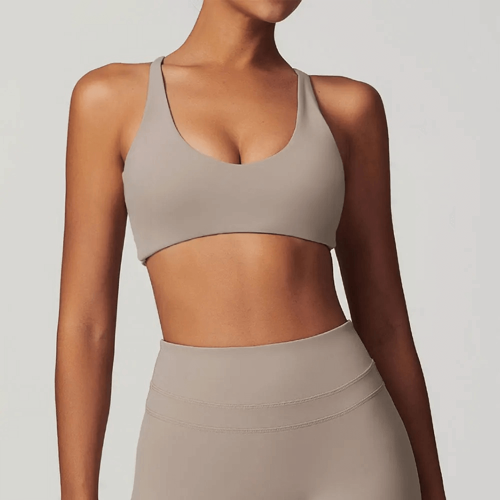 Woman wearing sleek beige racerback sports bra for fitness and yoga, highlighting breathable fabric and stylish design.