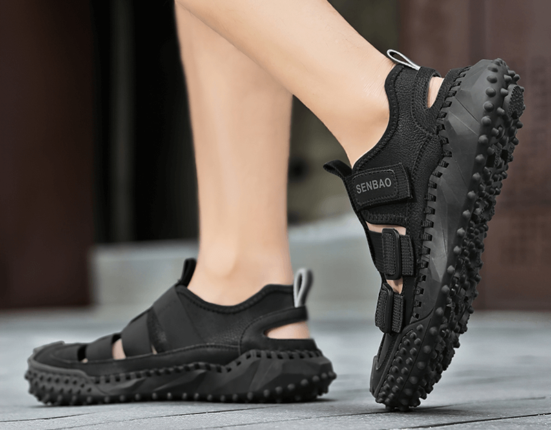 Side view of black elastic soles leather men's hiking sandals with breathable upper and rugged rubber outsole being worn outdoors.