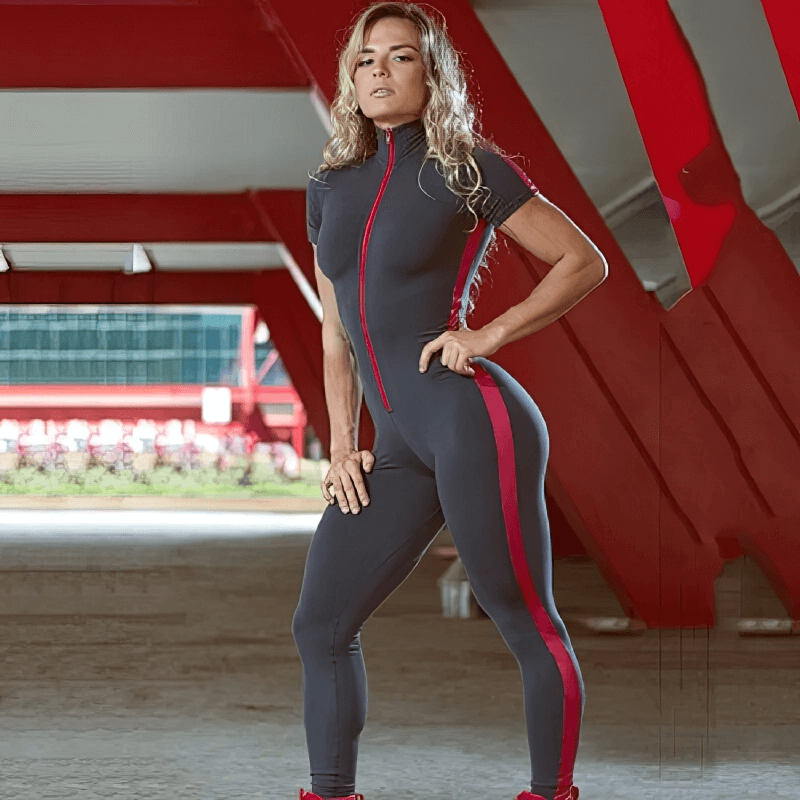 Woman posing in a stylish black and red elastic sports jumpsuit with short sleeves, perfect for yoga and workouts, under a modern structure.