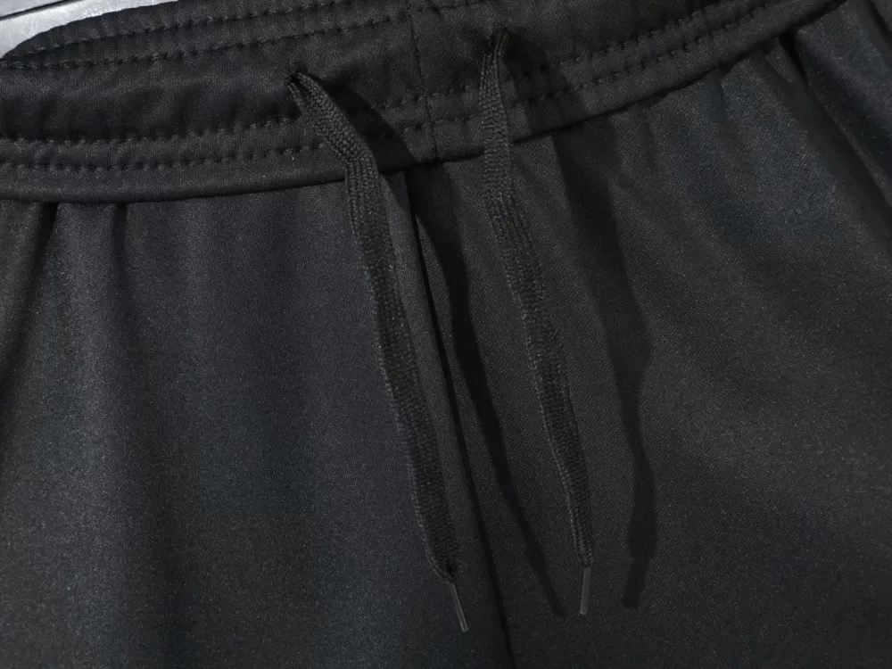 Close-up of black elastic waist men's training pants with drawstrings, featuring protective padded design.