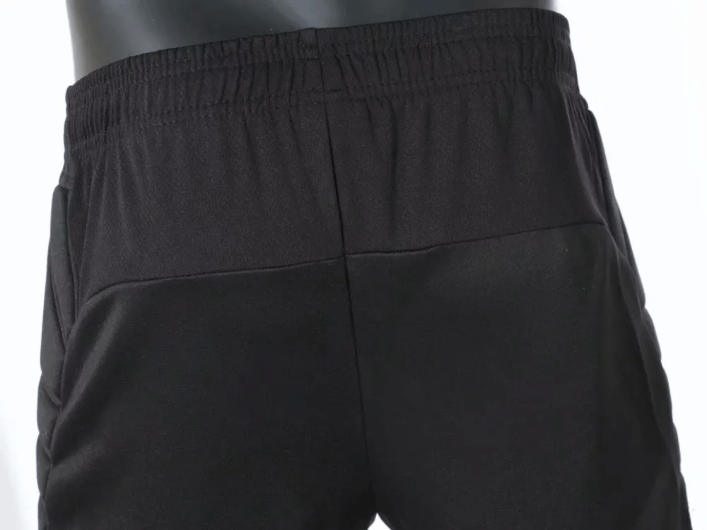 Close-up of black men's training pants with elastic waist and protective padding, perfect for comfortable and safe workouts.