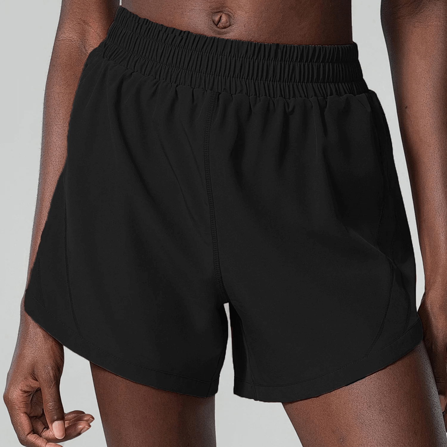 Person wearing black elastic waist shorts with pocket, ideal for active wear. Flexible and breathable for athletic and casual activities.