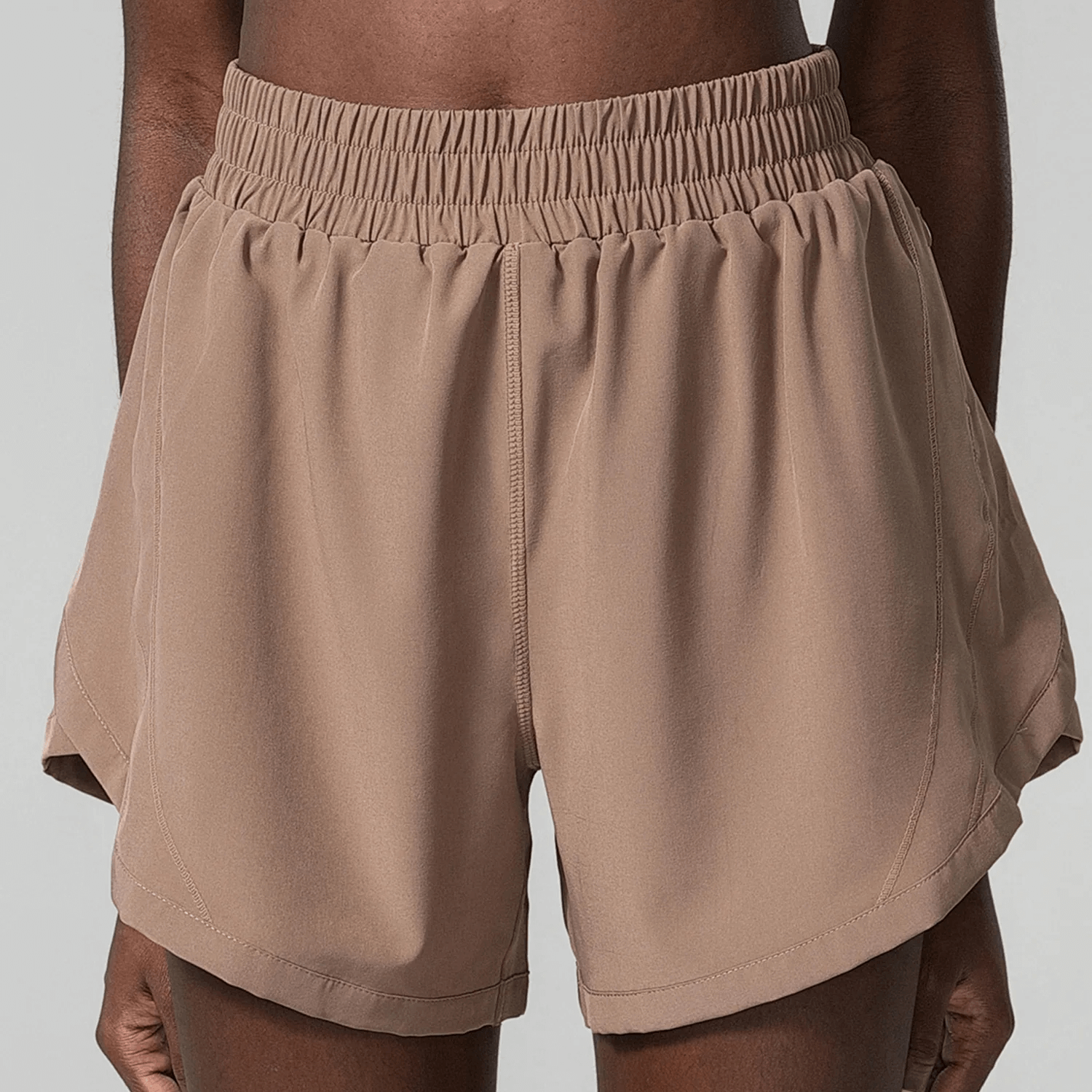 Elastic waist beige shorts for active wear, featuring a stretch waistband and breathable fabric. Perfect for athletic and casual use.