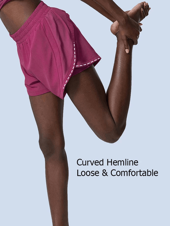 Model stretching in magenta active shorts with elastic waist and curved hemline, showcasing comfort and flexibility.