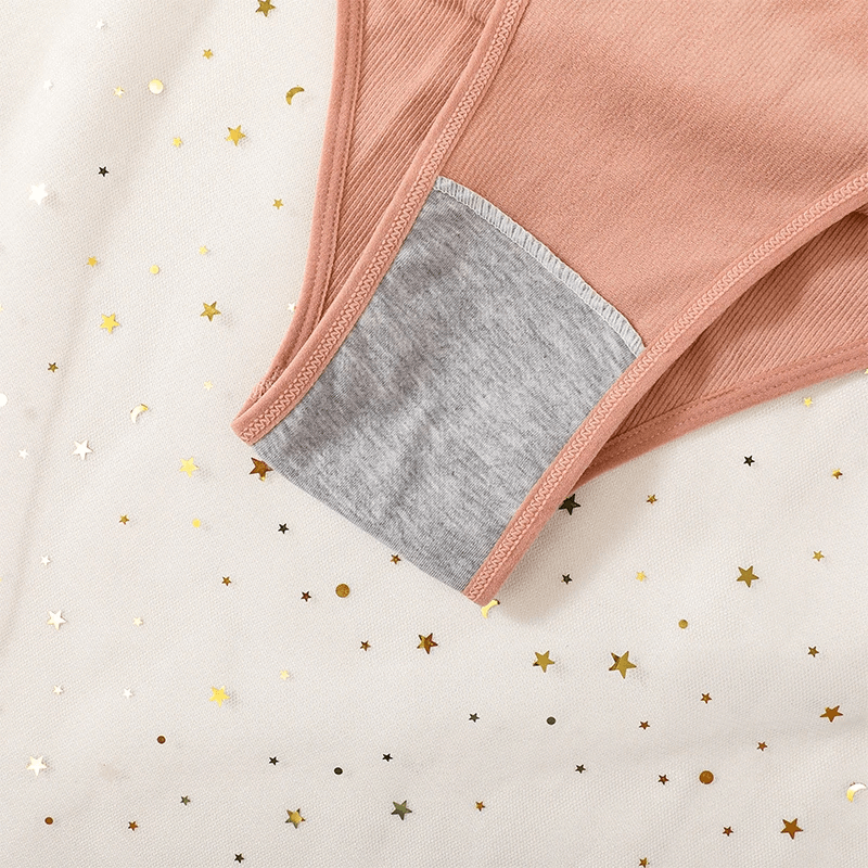 Close-up of pink high waist cotton briefs with gray lining, featuring breathable cotton-spandex blend and seamless design on starry fabric.