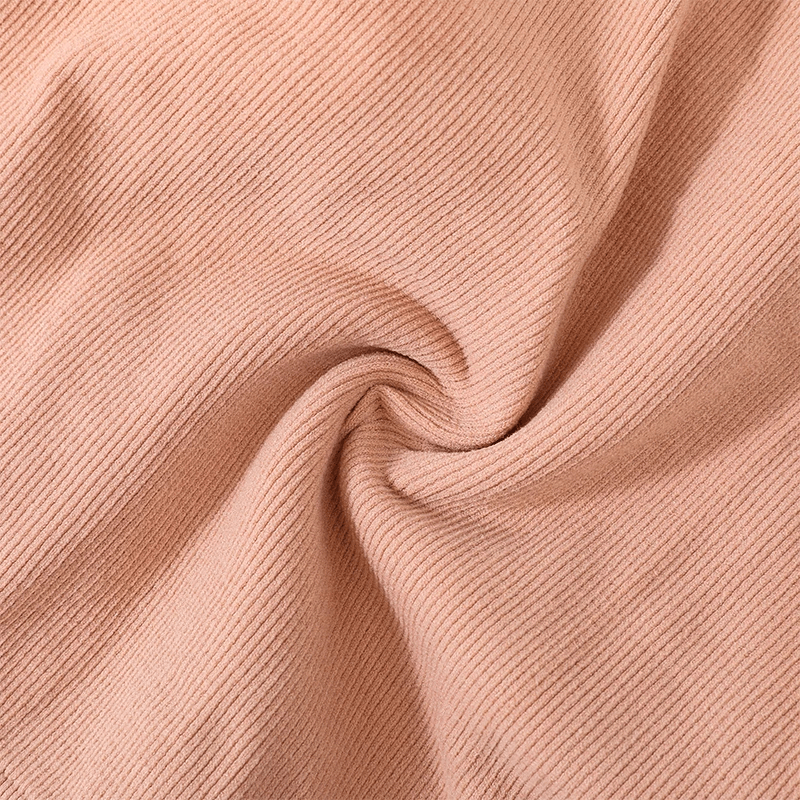 Close-up of soft, peach-colored, ribbed cotton-spandex fabric showcasing texture and stretch.