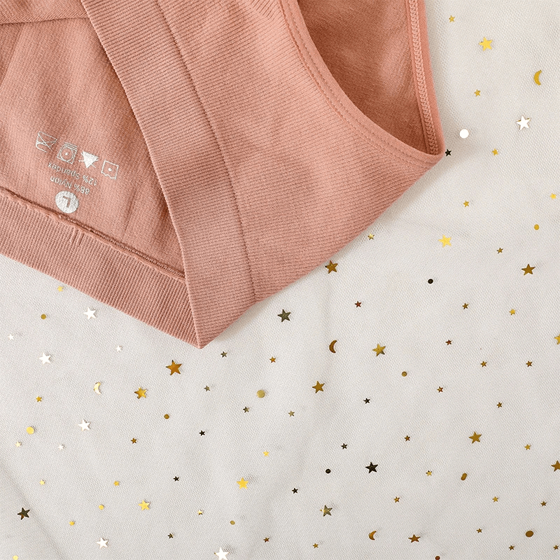 High waist pink cotton-spandex women's briefs with a seamless design, displayed on star-patterned fabric.