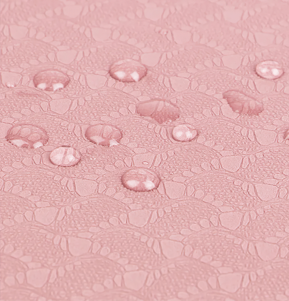 Close-up of water droplets on pink embossed elbow and knee mat, highlighting anti-slip, waterproof texture for yoga and fitness support.