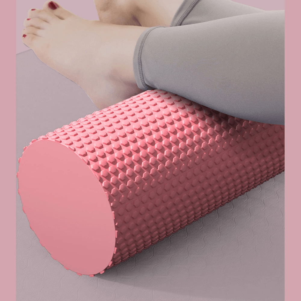 Person using pink hexagonal EVA foam yoga roller for muscle relief and flexibility on legs. Ideal for Pilates and stretching exercises.