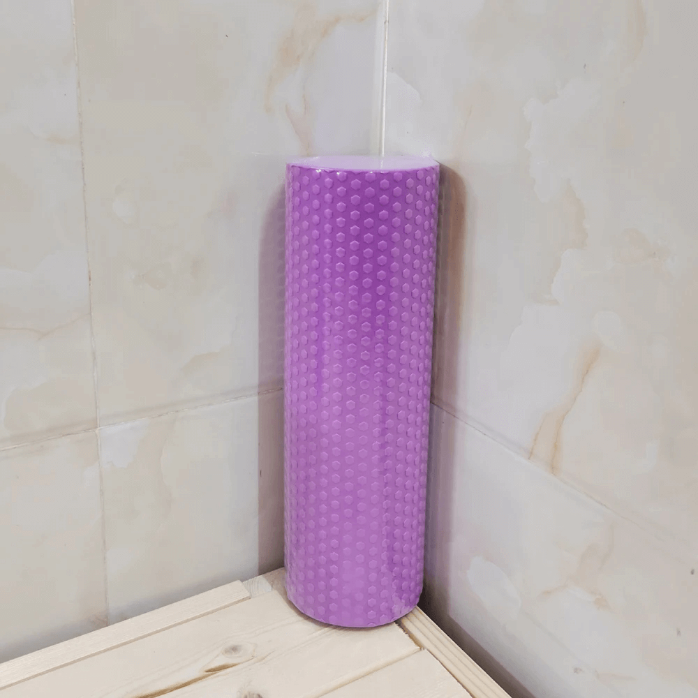 Purple hexagonal EVA foam yoga roller for Pilates, muscle relief, and stretching, enhancing flexibility and recovery, placed in a room corner.