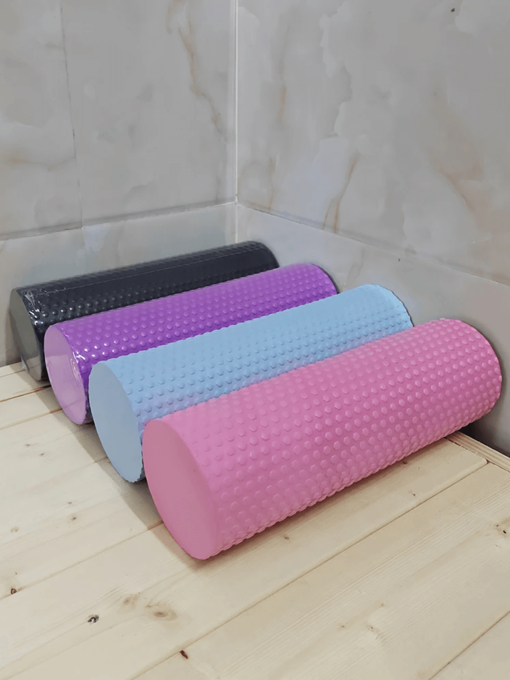 Hexagonal EVA foam yoga rollers in various colors for Pilates, stretching, and muscle relief on wooden floor.