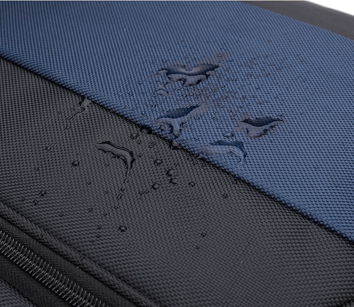 Close-up of water-resistant polyester fabric on an expandable travel suitcase, showing droplets on black and blue material.