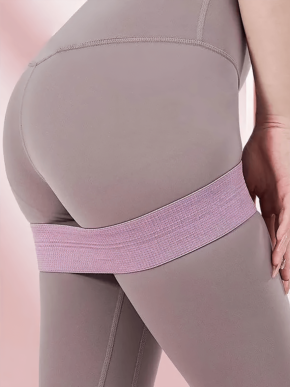 Elastic resistance band for home gym workout, ideal for Pilates and strength training. Durable fabric hip band in use for leg exercise.