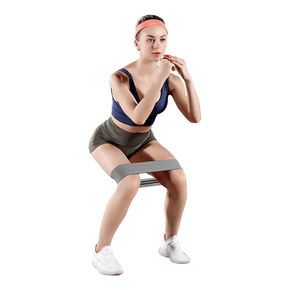 Woman using fabric resistance hip band for glute activation exercise.