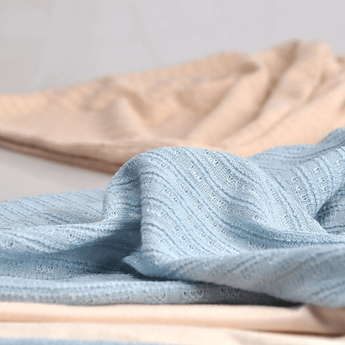 Close-up of soft blue and beige knit fabric texture, perfect for winter wear and cozy fashion accessories like beanies.