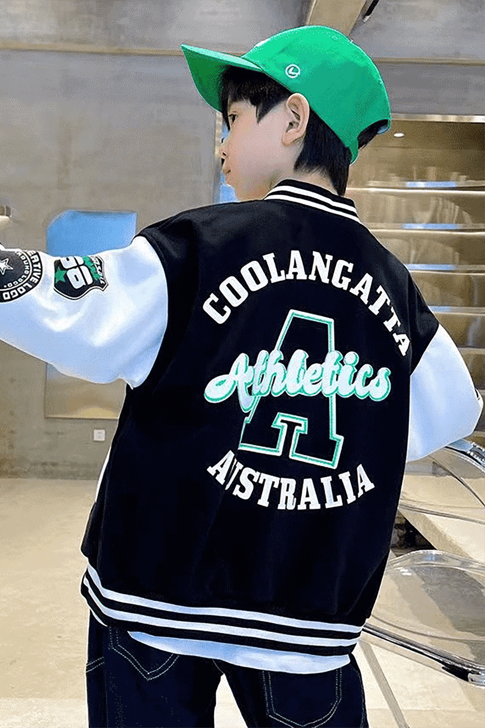 Teen boy in stylish baseball jacket and green cap, showcasing sporty outerwear from Coolangatta Athletics, Australia collection.