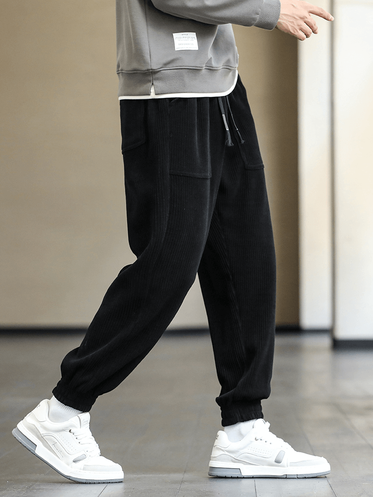 Man wearing black corduroy sweatpants with elastic hem and white sneakers, showcasing loose casual jogger style - SF1410