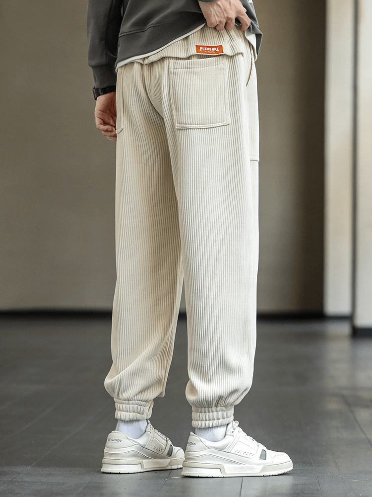 Man wearing Fashion Elastic Hem Corduroy Sweatpants with pockets, showcasing loose fit and stylish design, paired with sneakers.