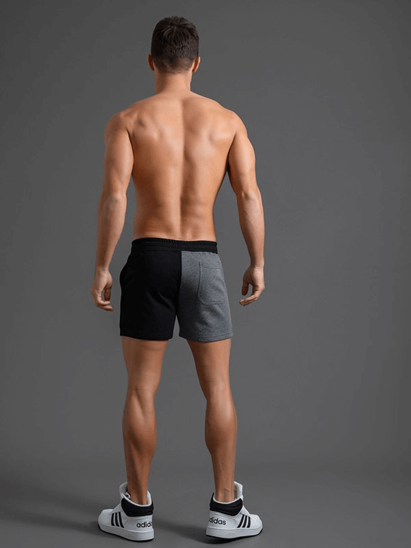 Back view of a man wearing fashion elastic waist cotton two-color shorts, featuring a stylish patchwork design and comfortable fit.