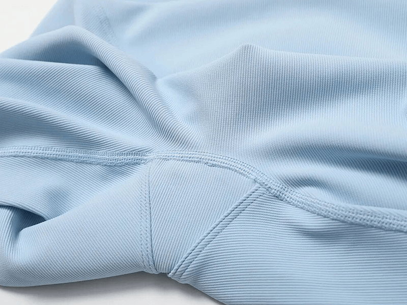 Close-up of light blue seamless sports fabric showcasing smooth texture and stitching detail.