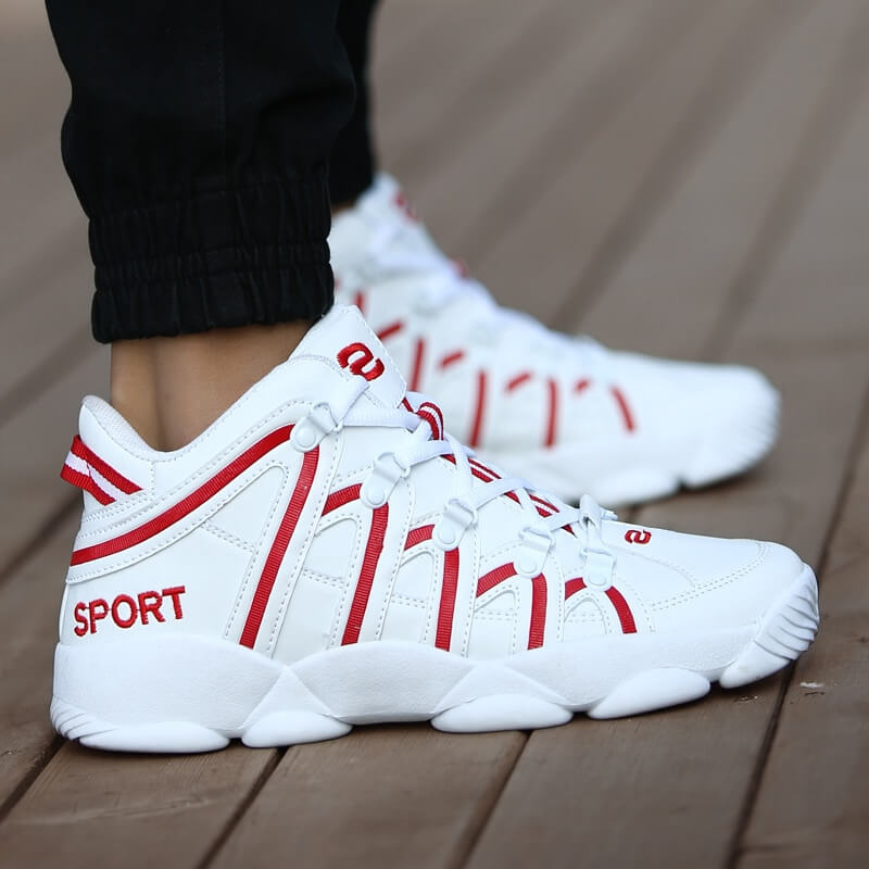 Unisex white and red lace-up sneakers, PU upper and rubber outsole, sporty design, shown worn outdoors.