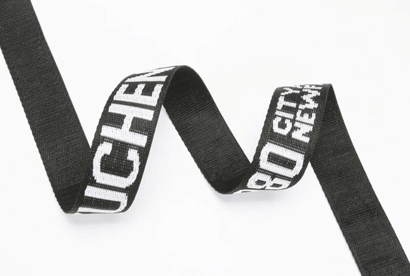 Stylish black and white ribbon with text pattern on white background, perfect for fashion accessories or decorative uses.