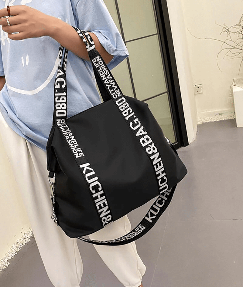 Stylish black nylon women's gym bag with logo straps, ideal for yoga and travel. Lightweight and spacious for active lifestyles.