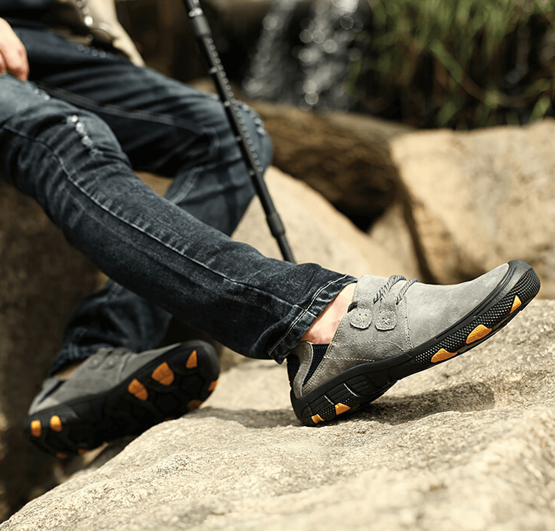 Stylish genuine leather trekking shoes for men on rocky terrain, featuring a breathable design and rugged rubber soles for outdoor adventures.
