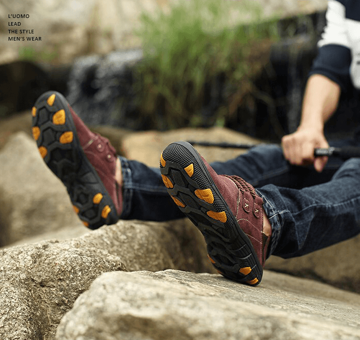 Person wearing fashion male breathable genuine leather outdoor trekking shoes, showing grip and style on rocky terrain.