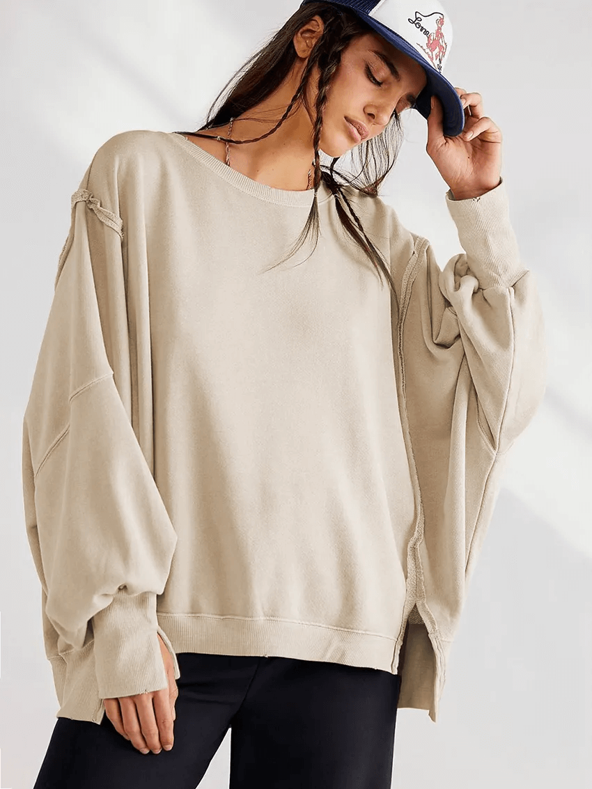 Woman wearing a loose, solid color drop-shoulder sweatshirt with three-quarter sleeves, perfect for casual style.