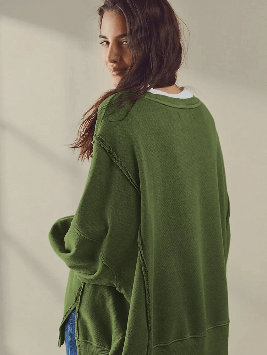 Woman wearing a green solid color drop shoulder loose sweatshirt, showcasing a casual look with an O-neck and three quarter sleeves.