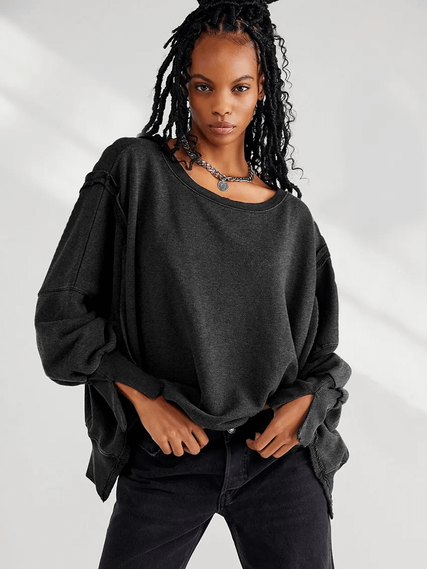 Woman wearing a loose black drop-shoulder sweatshirt with O-neck collar and three-quarter sleeves, styled for a casual look.