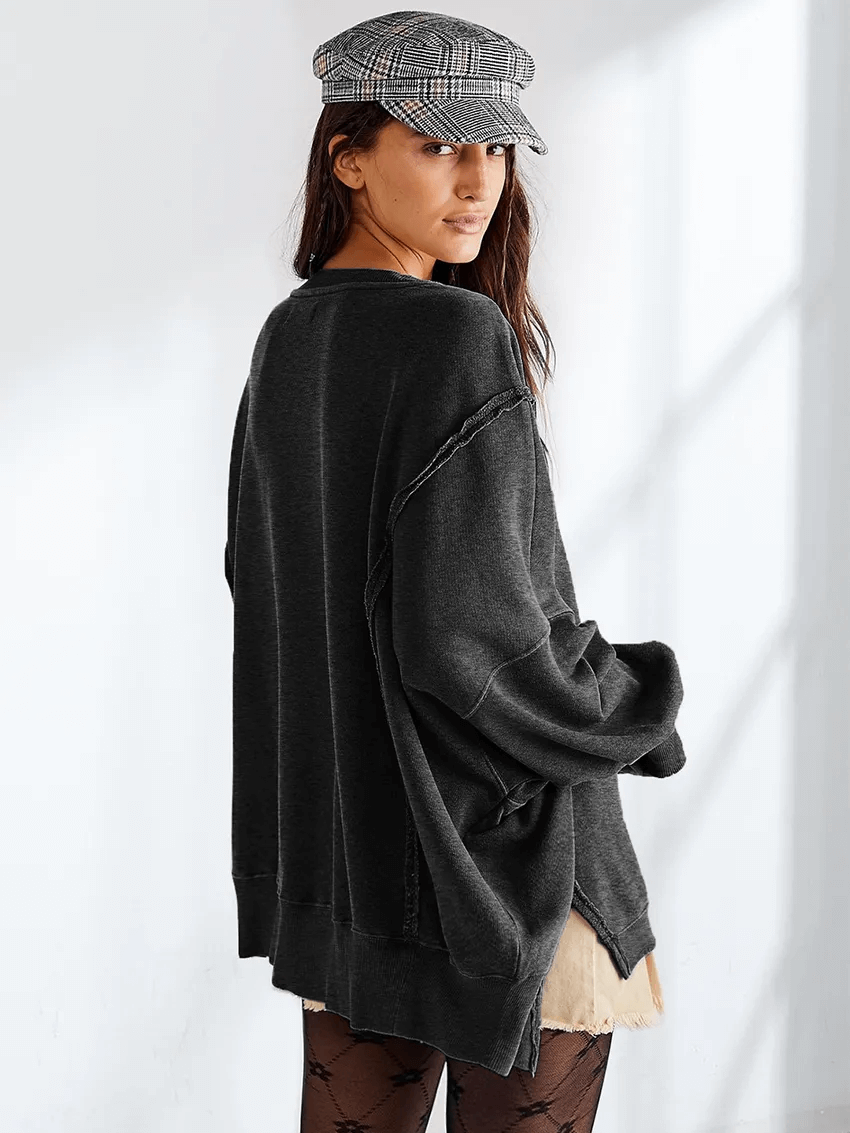 Woman wearing a loose solid color drop shoulder sweatshirt with a stylish cap, showcasing a casual and chic look.