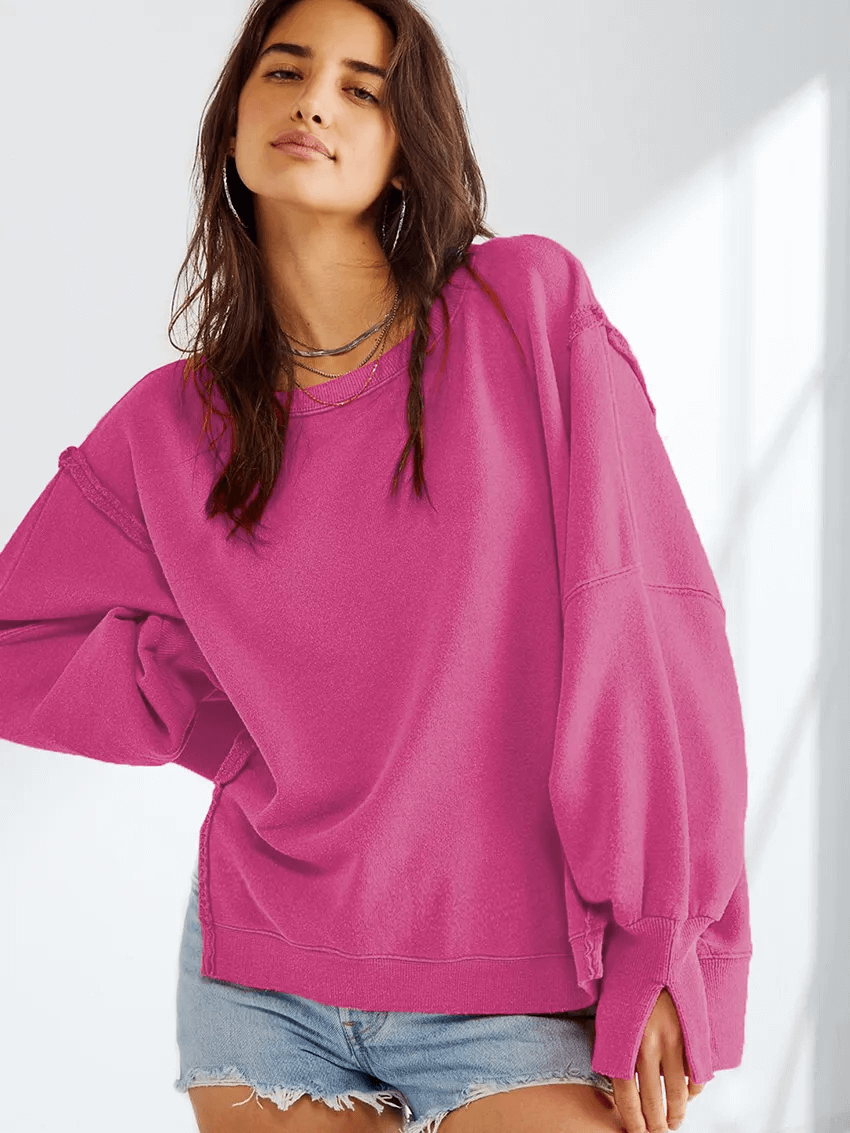 Woman wearing a pink solid color drop shoulder loose sweatshirt with O-neck and three-quarter sleeves, styled casually.