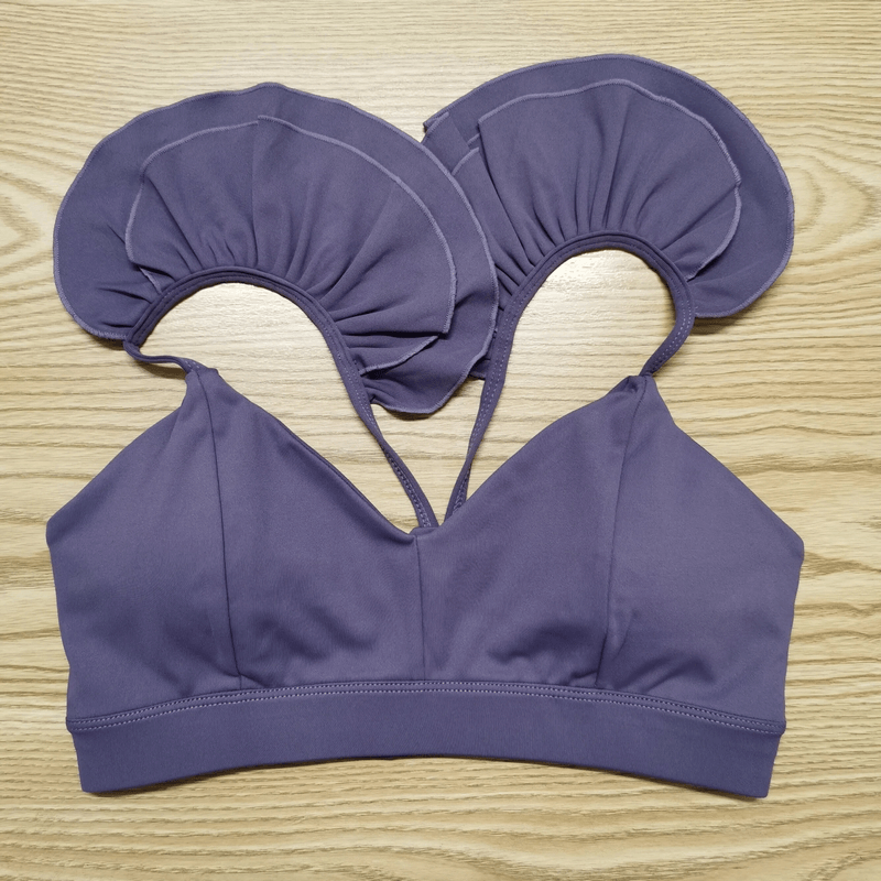 Purple fashion solid color elastic sports bra for women SF1740 on wooden table, ideal for yoga and running, with ruffle strap detail.