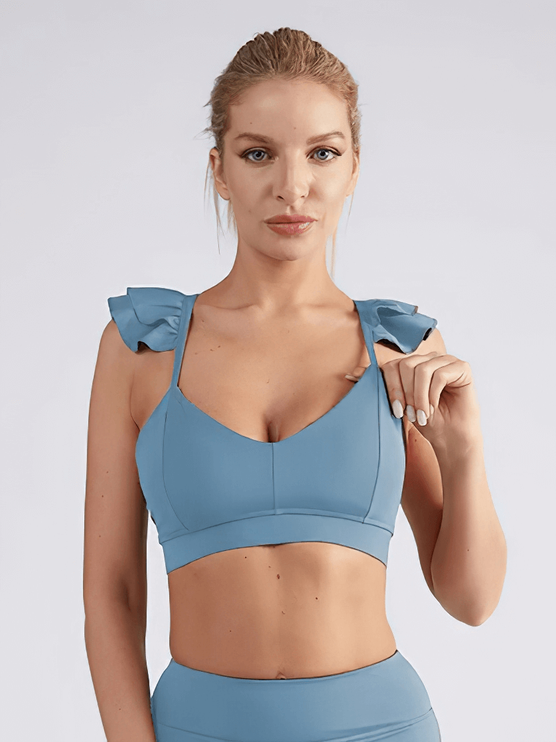 Woman modeling a blue solid color elastic sports bra for fitness activities, showcasing style and comfort fit for yoga or running.