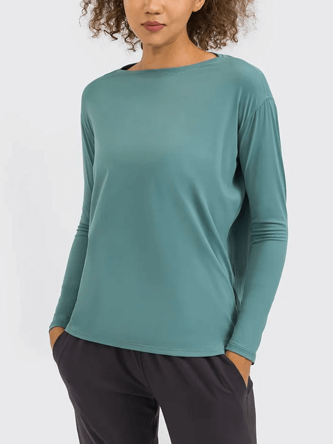 Model wearing solid color long sleeves loose gym top SF1821, made of durable nylon-spandex in teal, perfect for workouts.