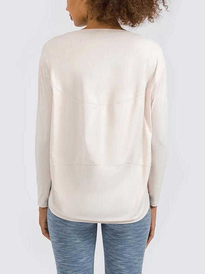 Back view of woman wearing a solid color long sleeve loose gym top with breathable fabric.
