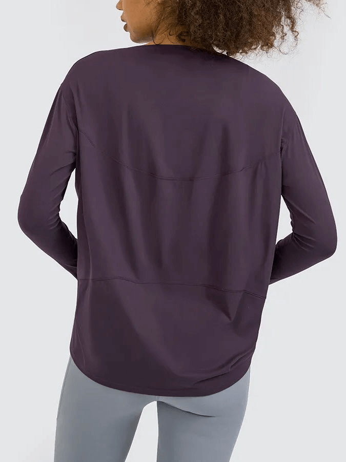 Woman wearing a fashion solid color long sleeves loose top for gym, showcasing breathable and quick-dry fabric.