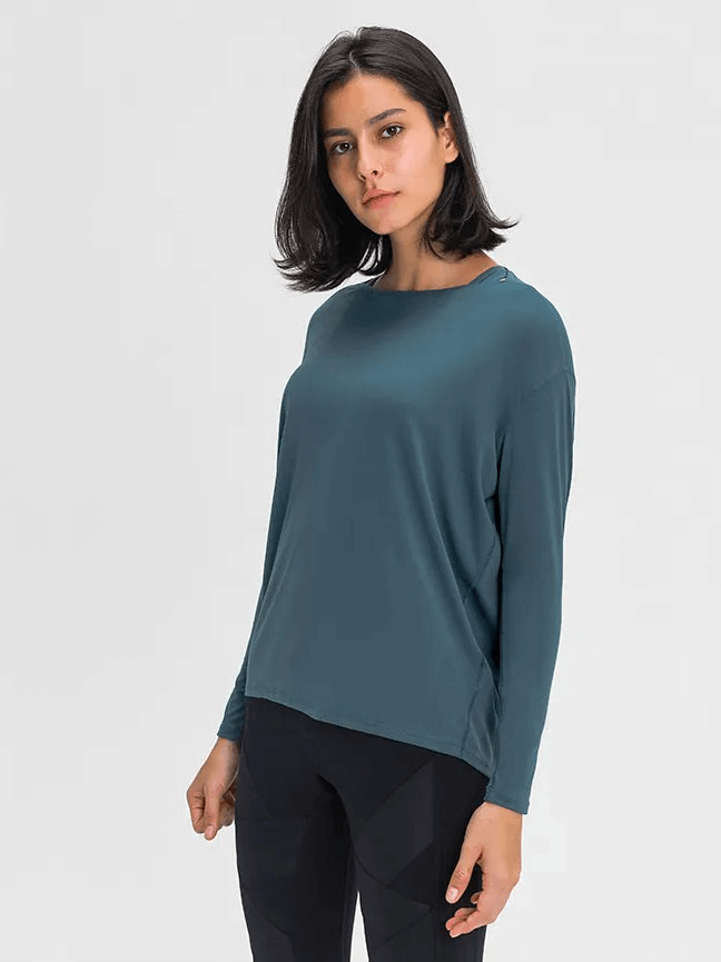 Woman wearing a blue solid color long sleeves gym top, showcasing comfort and style, perfect for workouts.
