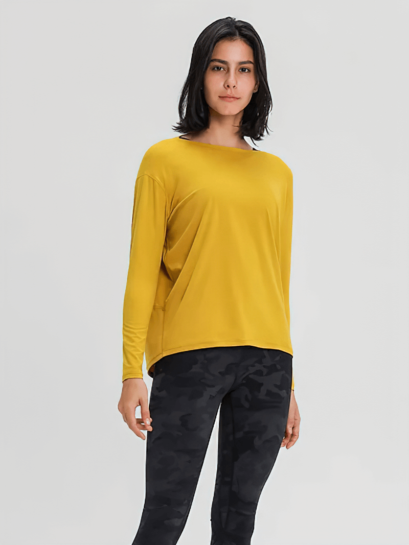 Model wearing a yellow solid color long sleeves loose top for gym, paired with black camo leggings, perfect for workout comfort.