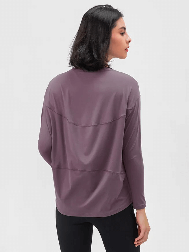 Back view of a woman wearing a purple long-sleeved loose gym top, showcasing the durable fabric and relaxed fit.