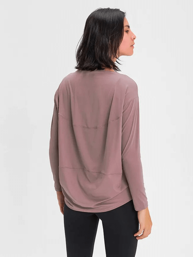 Woman wearing a mauve long-sleeve loose top for gym, back view, showcasing breathable fabric and comfortable fit.