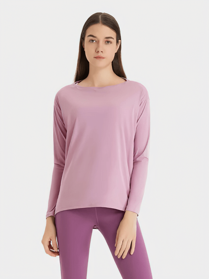 Woman wearing a pink solid color long sleeves gym top, showcasing comfortable and durable workout fashion with sleek design.