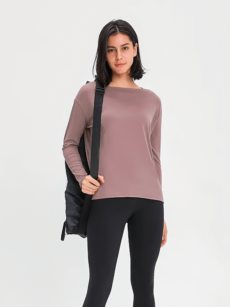 Woman wearing a fashion solid color long sleeves loose top for gym with a shoulder bag, perfect for workouts.